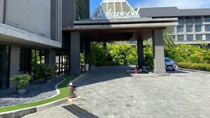 A hotel entrance with a covered walkway, a sign reading 'Deluxe,' and a parking area with a car. - Oakwood Lavaya Nusa Dua Bali (Benoa)