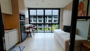 Un apartamento moderno con cocina, comedor y un ventanal con vistas a edificios y vegetación.
