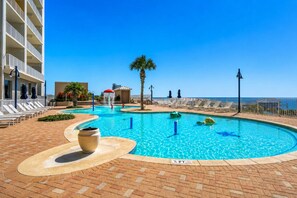 Ein Swimmingpool mit Liegestühlen, einer Palme und Blick auf den Ozean.