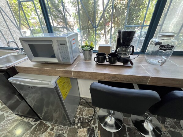 Eine Küche mit Mikrowelle, Kaffeemaschine und Wasserspender.