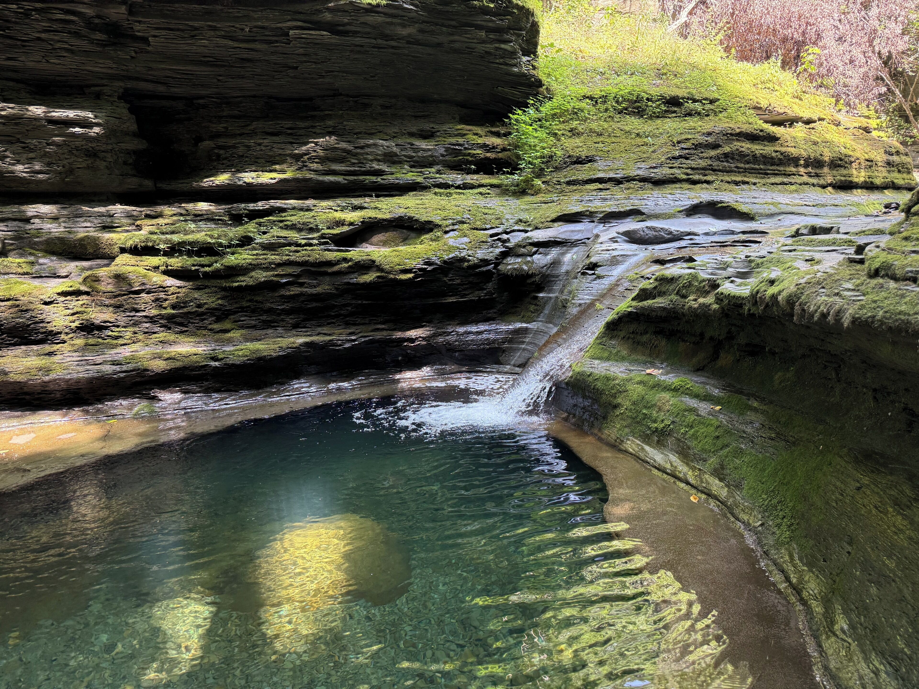 Une formation rocheuse naturelle avec une petite cascade et de l’eau claire.