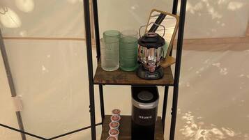 A shelf with a kettle, cups, a lantern, and towels.