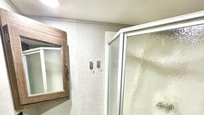 Ein Badezimmer mit Waschtisch, Spiegel, Waschbecken und Duschkabine.