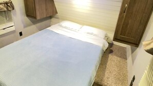 Ein gemütliches Schlafzimmer mit Bett, Holz-Kopfteil und kleinem Fenster.