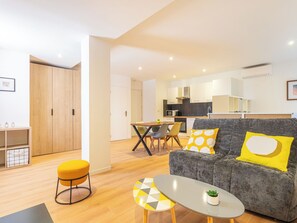 Ein modernes Wohnzimmer mit einer Couch, einem Couchtisch und einem gelben Hocker.