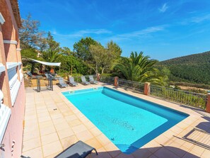 Ein Pool mit Liegestühlen, einer überdachten Sitzgelegenheit und Blick auf die umliegende Landschaft.