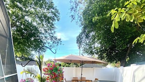 A patio with a table and chairs, a hanging flower arrangement, and a grill. - Luxury Pool home, 1 mile from Bush Gardens (Tampa)
