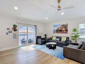 Ein modernes Wohnzimmer mit Deckenventilator, einem großen Fenster mit Aussicht und einem Essbereich mit Sitzgelegenheit im Freien.