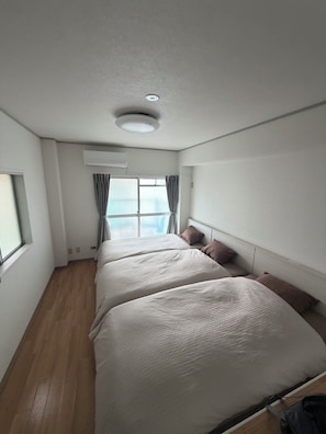 A hotel room with a large bed, a window, an air conditioning unit, and a ceiling light. - Within walking distance of Shibuya, Harajuku and Shinjuku! 86 sqm spacious family size apartment with balcony (渋谷区)