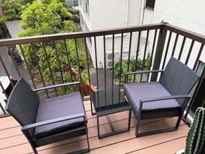 A balcony with two black wicker chairs and a small table, surrounded by a metal railing. - Within walking distance of Shibuya, Harajuku and Shinjuku! 86 sqm spacious family size apartment with balcony (渋谷区)