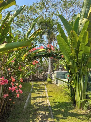 Ein Gartenpfad, umgeben von üppiger Vegetation und blühenden Pflanzen.