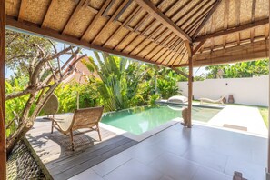 A pool area with a wooden deck, a wicker chair, and a thatched roof structure. - Tropical 2 BDR Joglo Villa•Private Pool•Heart of Uluwatu (pecatu)