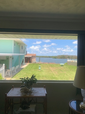 Ein Zimmer mit Seeblick, ein kleiner Tisch mit einer Pflanze und eine Lampe.