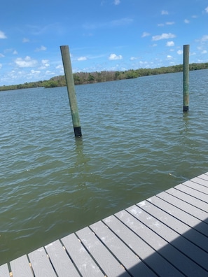 Eine hölzerne Mole, die sich in ruhiges Wasser erstreckt, mit blauem Himmel darüber.