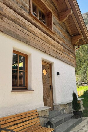 A log cabin with a wooden exterior, a white wall, a wooden door, and a bench outside. - Chalet Auszeit by Interhome (Flattach)