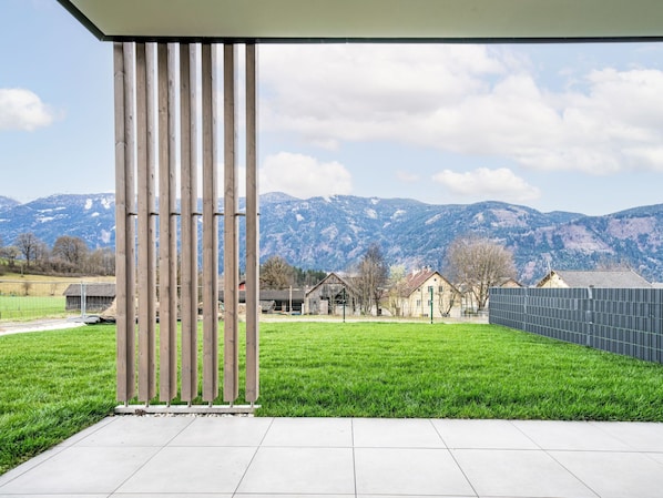 Ein modernes Gebäude mit Flachdach, einer großen, offenen Terrasse und Blick auf Berge im Hintergrund.