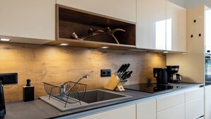 Eine moderne Küche mit Holzrückwand, einer Edelstahlspüle und einer Kaffeemaschine.