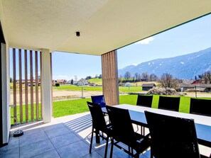 Ein moderner Essbereich im Freien mit Blick auf eine Berglandschaft.