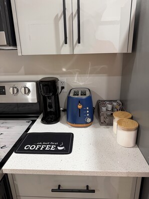 Cozinha com cafeteira, torradeira e dois potes na bancada.