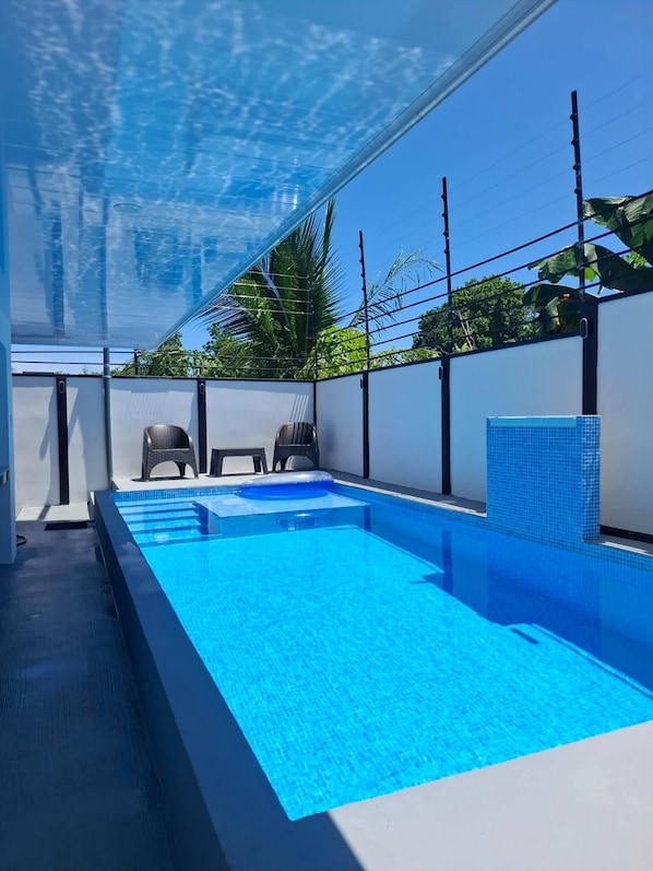 Una piscina interior rectangular con agua azul cristalina, rodeada de paredes blancas y un techo de vidrio.