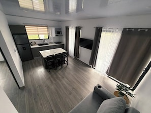 Una cocina moderna con comedor, sofá y ventana con cortinas.