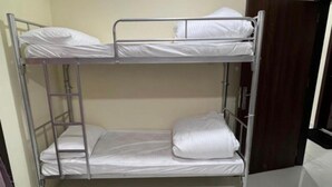 A bunk bed with metal railings and white bedding.