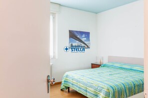A bedroom with a bed, a radiator, a poster on the wall, and a window.