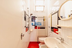 Une salle de bain comprenant des toilettes, un bidet et un lavabo, ainsi qu’un miroir et une fenêtre.