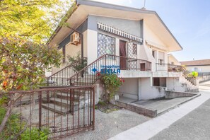 Un bâtiment à deux étages doté d’un balcon, d’un escalier et d’une entrée fermée par un portail.