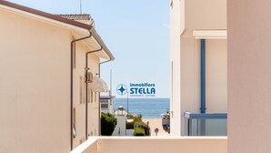 Una calle estrecha flanqueada por edificios, con vista despejada al mar, y un letrero de 'immobiliare STELLA' que indica servicios inmobiliarios.