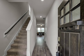 Ein Flur mit Teppichstufen, einer dunklen Holztür und einem Deckenventilator.