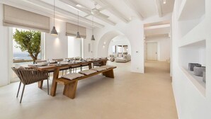 Un comedor amplio con una larga mesa de madera, bancos e iluminación colgante.