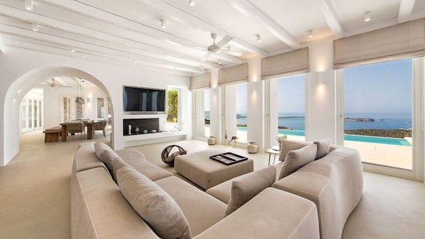 Un salón espacioso con un sofá grande, un televisor de pantalla plana y una zona de comedor con mesa y sillas.