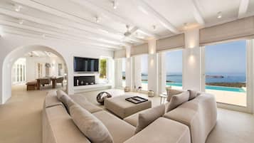 A spacious living room with a large sofa, a flat-screen TV, and a dining area with a table and chairs.