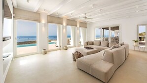 Amplia sala de estar con un sofá seccional grande, comedor y vista a la playa.