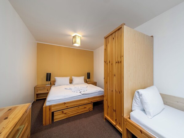 A room with a bed, a wooden wardrobe, a bedside table, and a wall-mounted light fixture. - Janský Potok by Interhome (Janské Lázně)