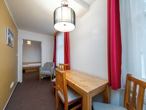 A room with a wooden table, two chairs, a ceiling light fixture, and a door leading to another room. - Janský Potok by Interhome (Janské Lázně)