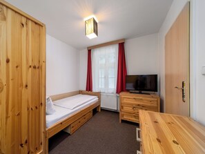 A small, well-lit room with a single bed, a TV, a wooden wardrobe, and a desk. - Janský Potok by Interhome (Janské Lázně)