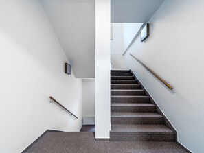 Eine moderne Treppe mit Handlauf, einer weißen Wand und einer Decke mit Oberlicht.