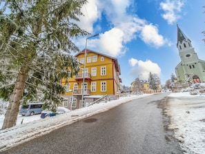 A snow-covered street with a yellow building and a church. - Janský Potok by Interhome (Janské Lázně)