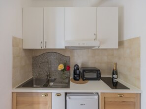 Eine kleine Küche mit Spüle, Toaster, Kaffeemaschine und einer Weinflasche.