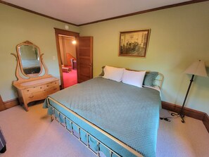 Un dormitorio con cama, cómoda, espejo y un cuadro en la pared.