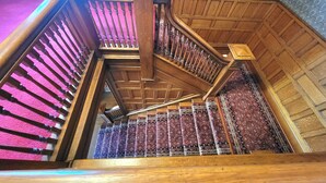Una escalera de madera con barandilla y un suelo estampado.