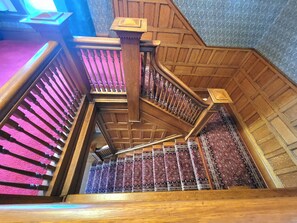 A wooden staircase with a handrail and a patterned carpet.