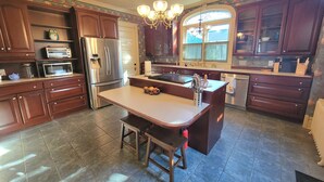 Una cocina con isla central, electrodomésticos de acero inoxidable y armarios de madera oscura.