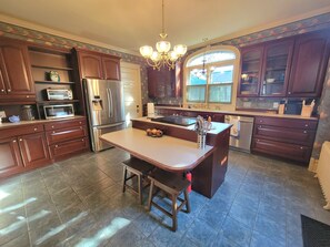 Una cocina con isla central, electrodomésticos de acero inoxidable y armarios de madera oscura.
