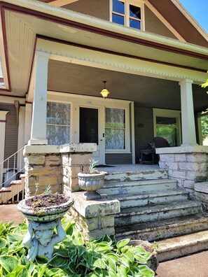 A house with a porch, stone steps, and a potted plant.