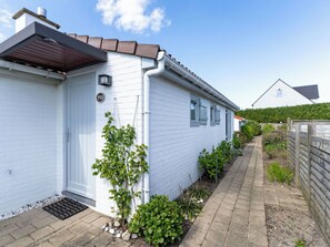 A white building with a number plate, a small garden, and a paved pathway. - Cosy apartment in villa for 6 people with WIFI, TV and terrace (De Haan)