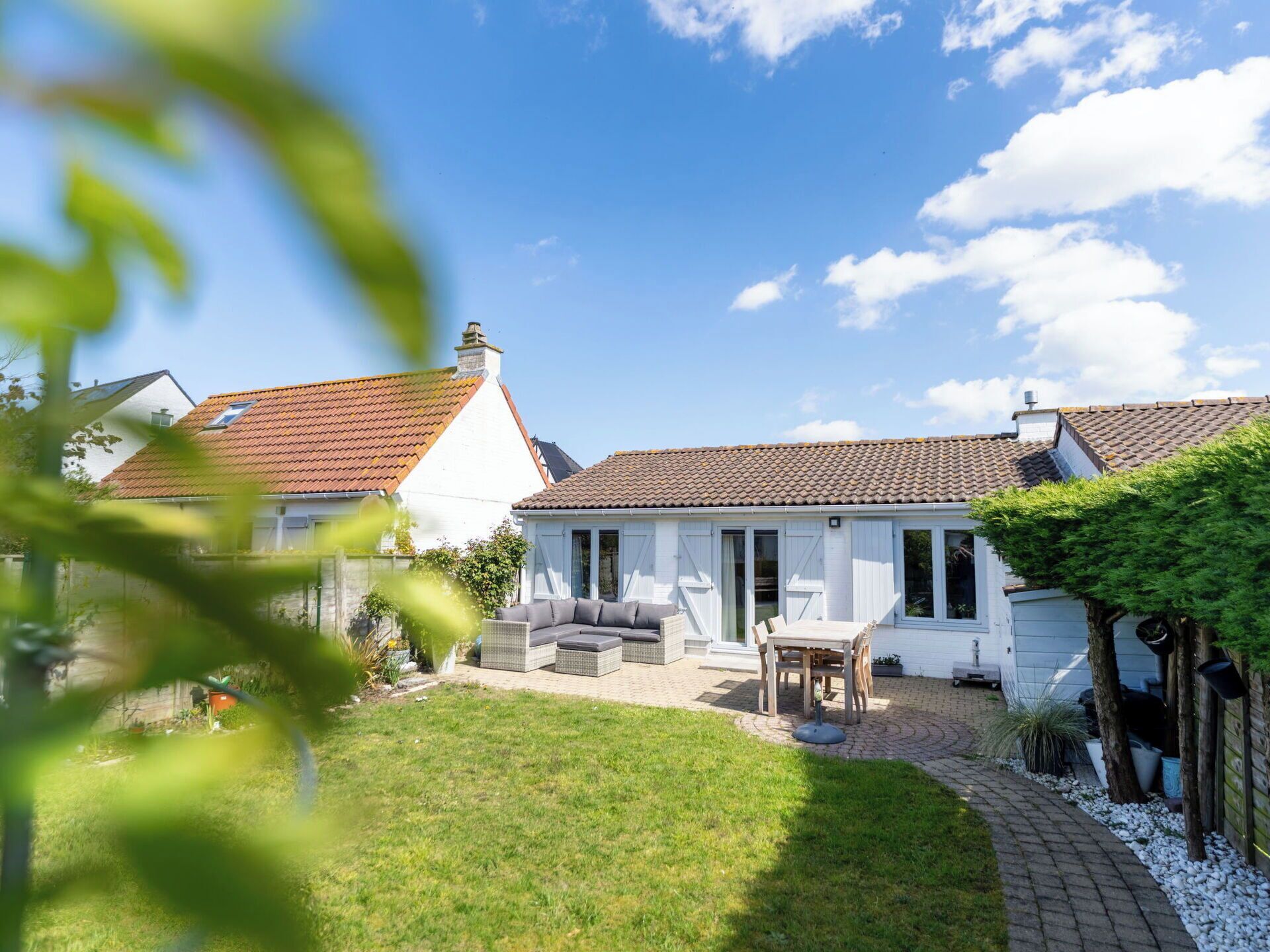 Une maison avec un toit en tuiles, un patio couvert et une pelouse.