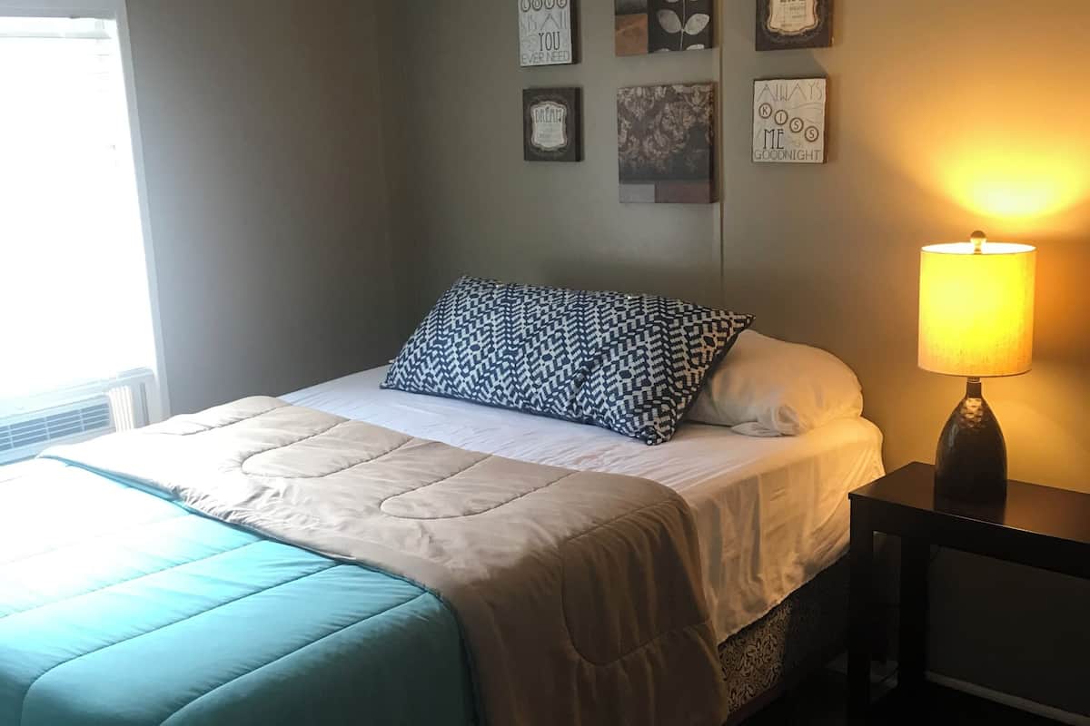 A bedroom with a bed, a bedside lamp, and wall art.